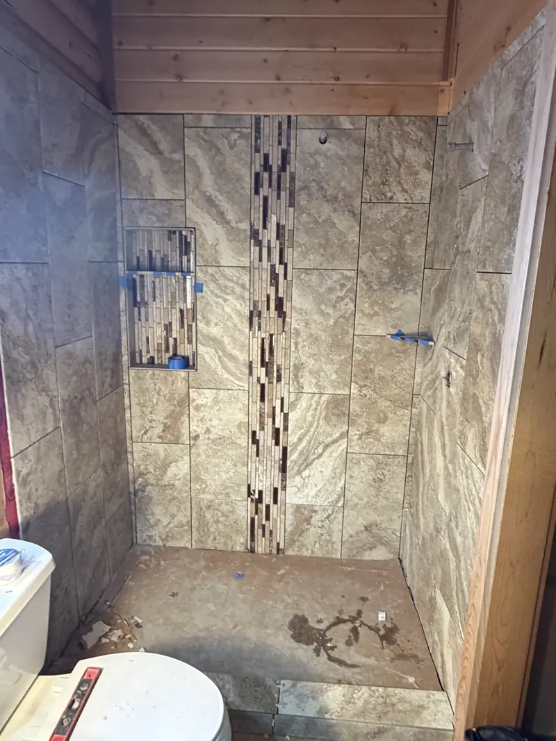 Walk-in shower with large-format stone-look tile, a vertical mosaic accent strip and a matching recessed niche